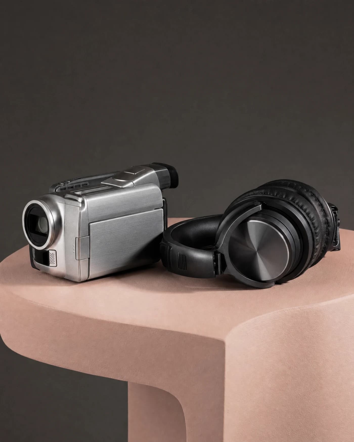 Silver video camera and headphones on a pink studio plinth